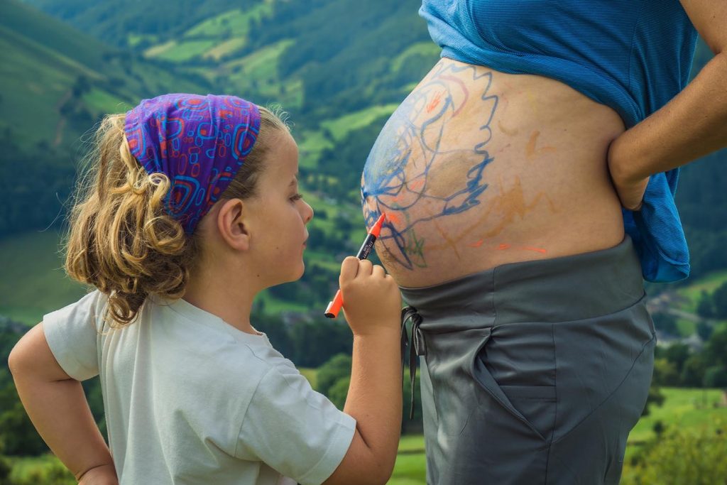 Niño pintando barriga embarazada